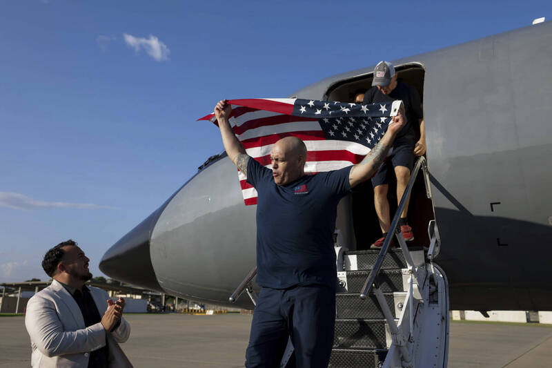 美国换回10名囚犯，获释其中一人到达机场后挥舞国旗。（美联）