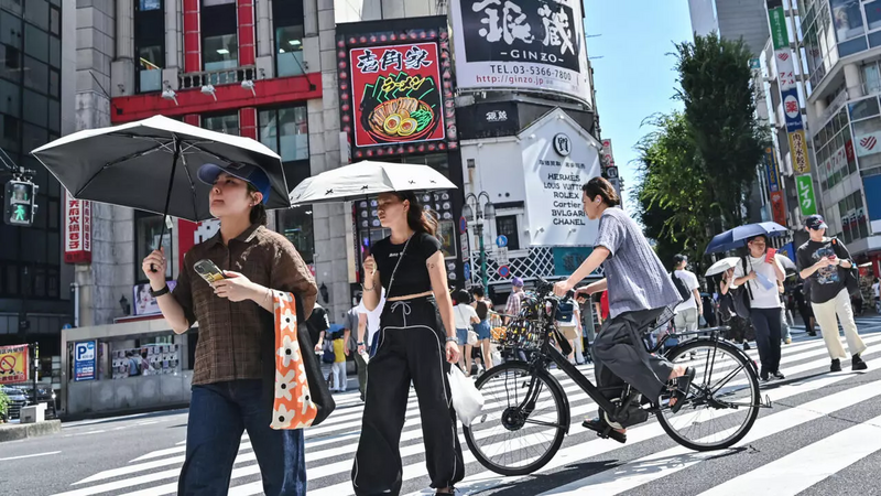 东京新宿歌舞伎町街头，行人撑伞遮阳或戴帽防晒，以因应酷暑高温来袭。日本多地近期气温飙破摄氏40度，创下观测纪录新高，引发热伤害通报激增。（法新社）