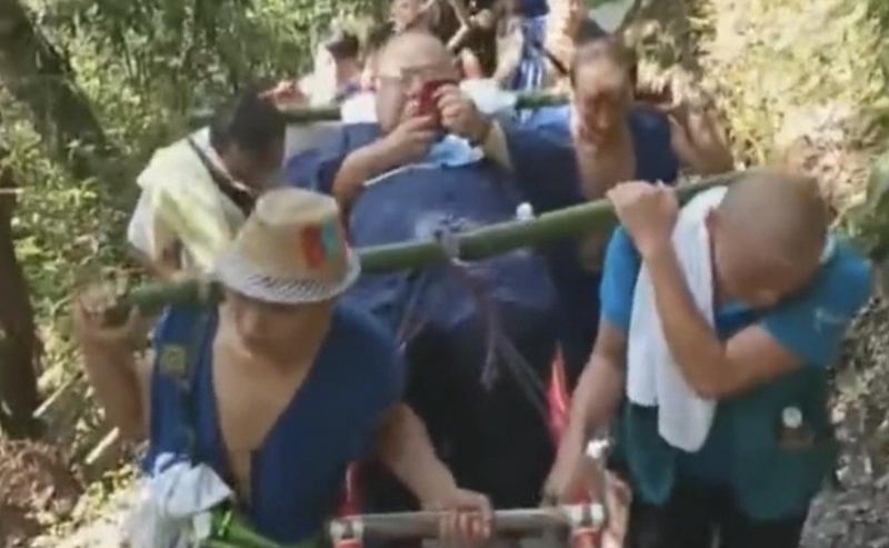 中国一名体重约130公斤的男子，包下9名轿夫抬轿往返42公里的峨眉山风景区。（图撷取自微博）