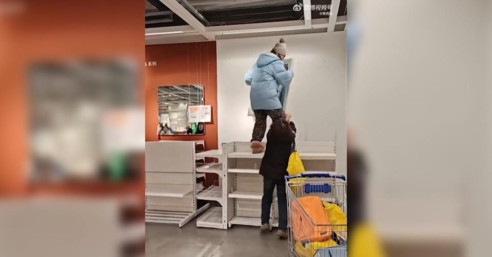 門市現場亂象叢生，兩名大媽為了搶一面鏡子，其中一人不顧危險直接爬上貨架。（圖／翻攝自微博@黃西炮）